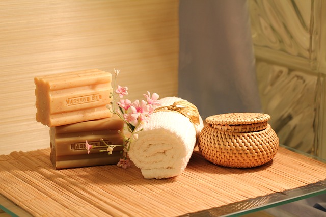 Spa still-life of handmade soap bars, rolled towel, wicker jar and blossoms