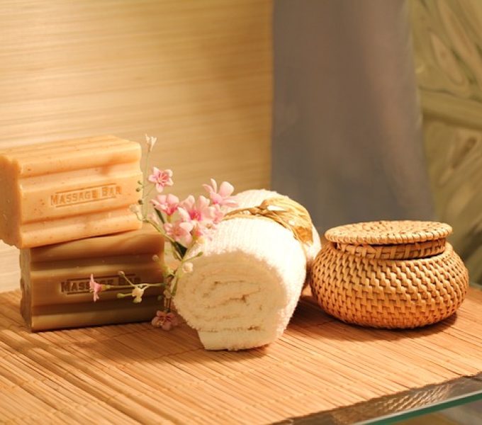 Spa still-life of handmade soap bars, rolled towel, wicker jar and blossoms