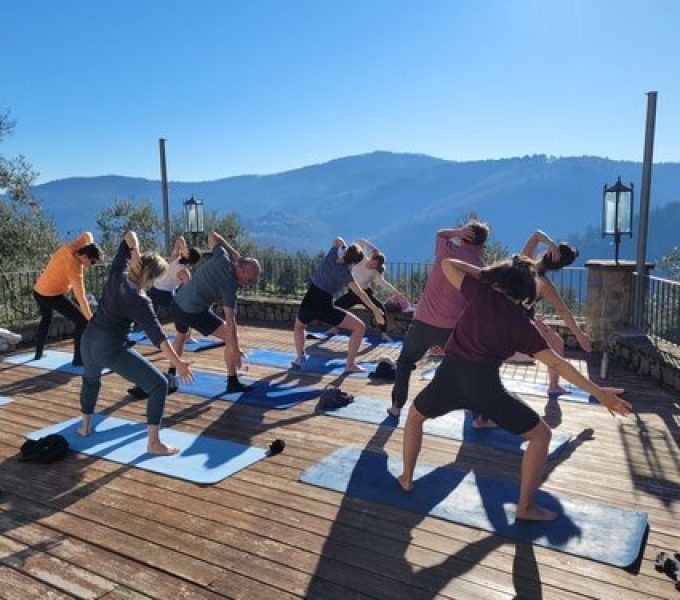 Outdoor yoga class twists on mountain-view deck beneath clear blue sky
